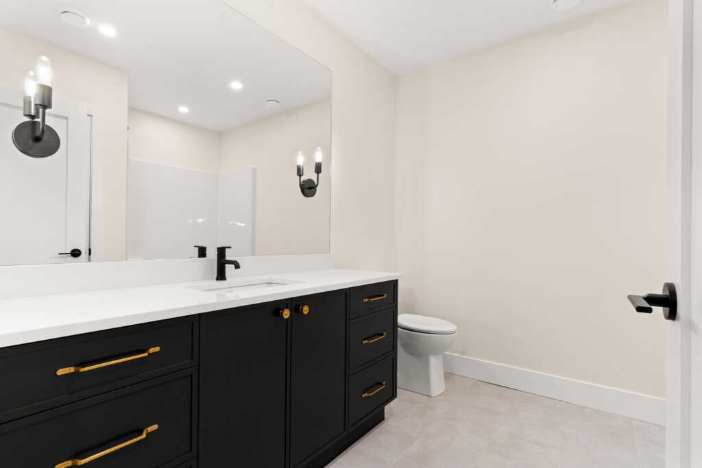 Basement bathroom with dark cabinets and gold accents
